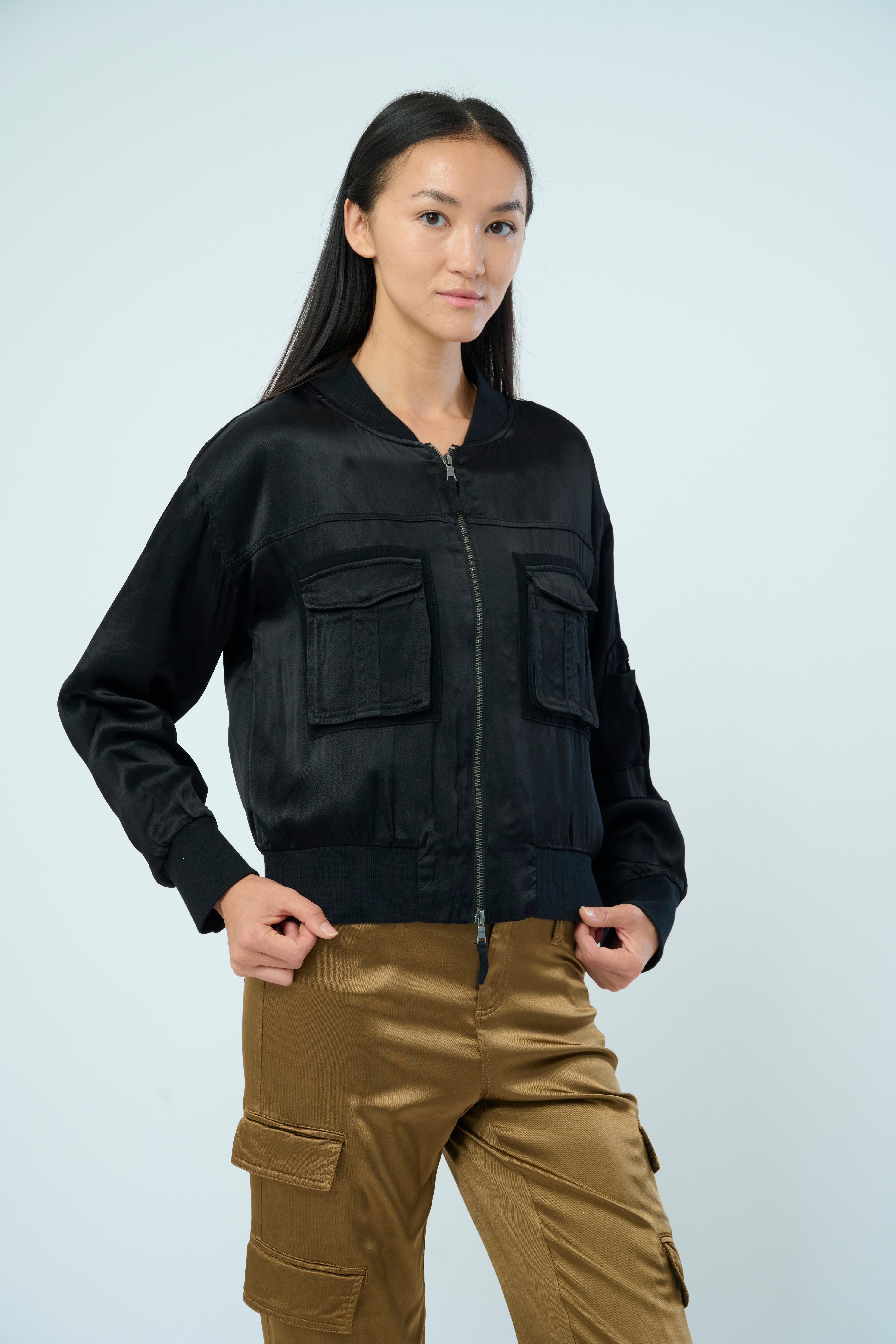 Front view of a tall female model with long black hair confidently posing wearing our black colored Dazie flight jacket from Marrakech Clothing.