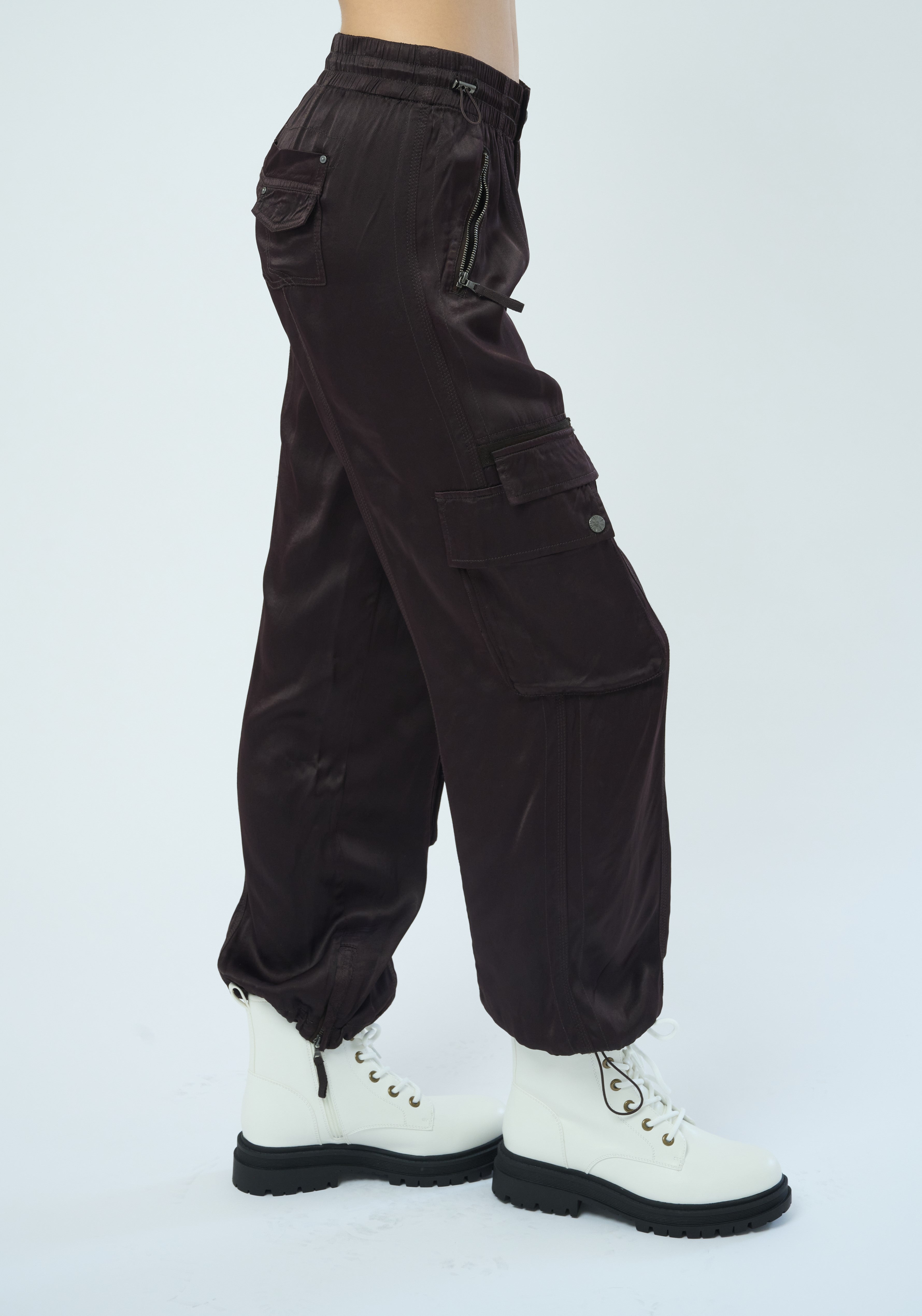 Side view of a tall female model  confidently posing wearing our dark chocolate colored Enika Viscose Satin Twill Cargo Jogger pant from Marrakech Clothing.