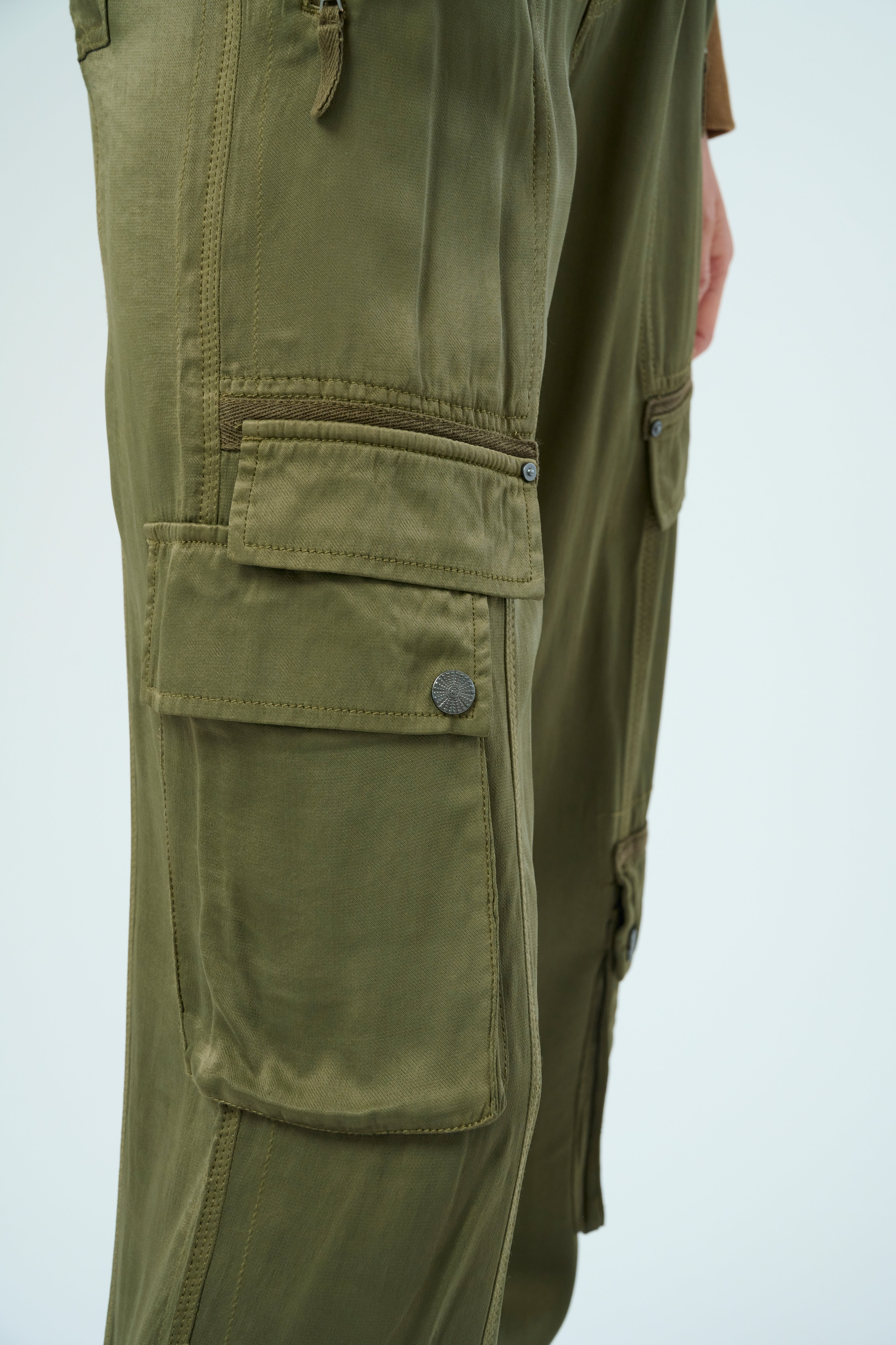 Closeup pocket detail side view of a tall female model posing wearing our pine colored Enika Viscose Satin Twill Cargo Jogger pant from Marrakech Clothing.