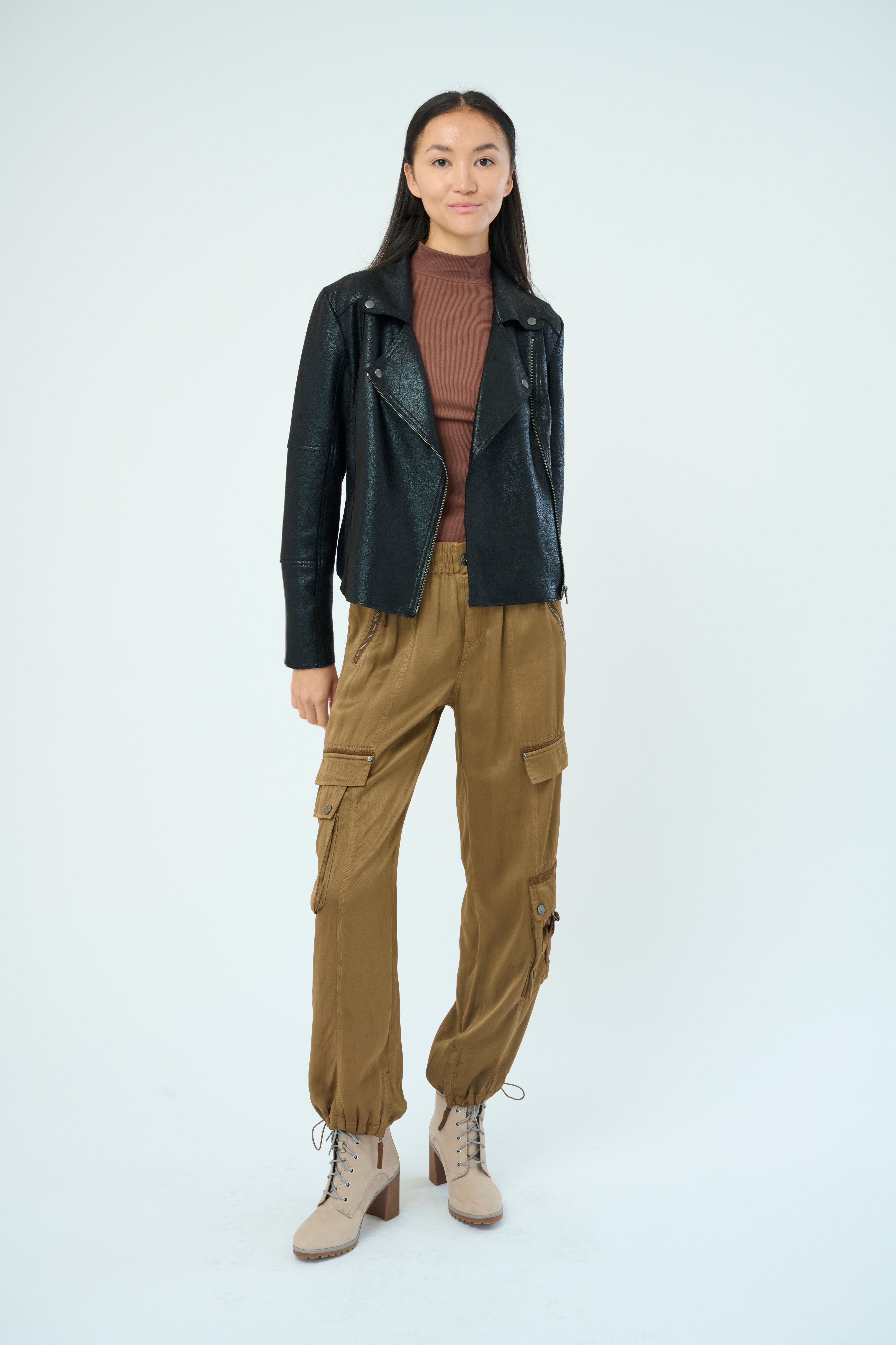 Front view of a tall female model with long black hair confidently posing wearing our cheetah colored Enika Viscose Satin Twill Cargo Jogger pant from Marrakech Clothing.